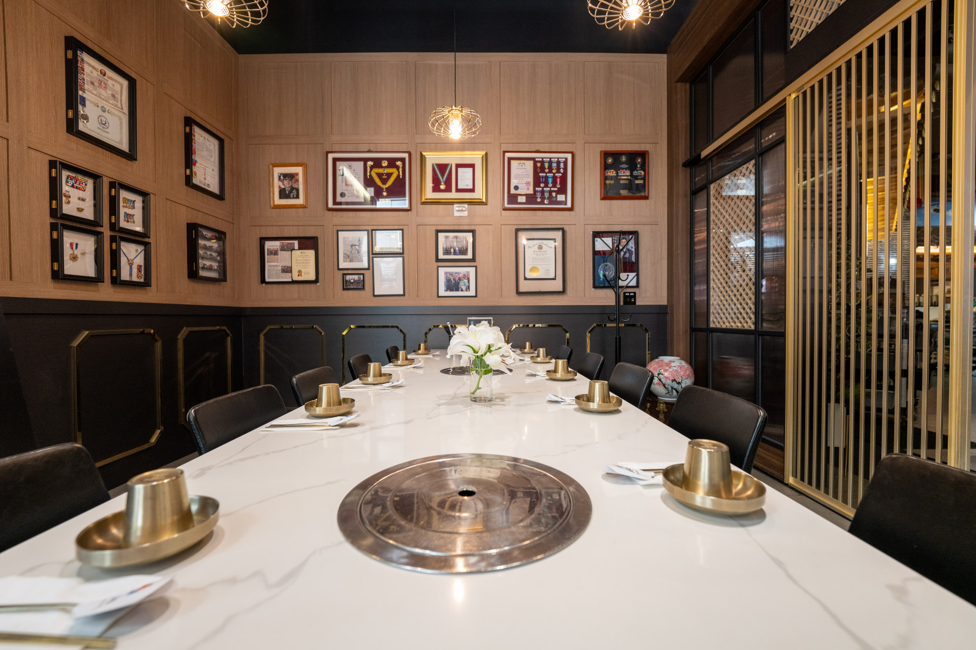 The Honor Room at Koho Korean BBQ House, set for a group dinner with tabletop grills and walls of service honors